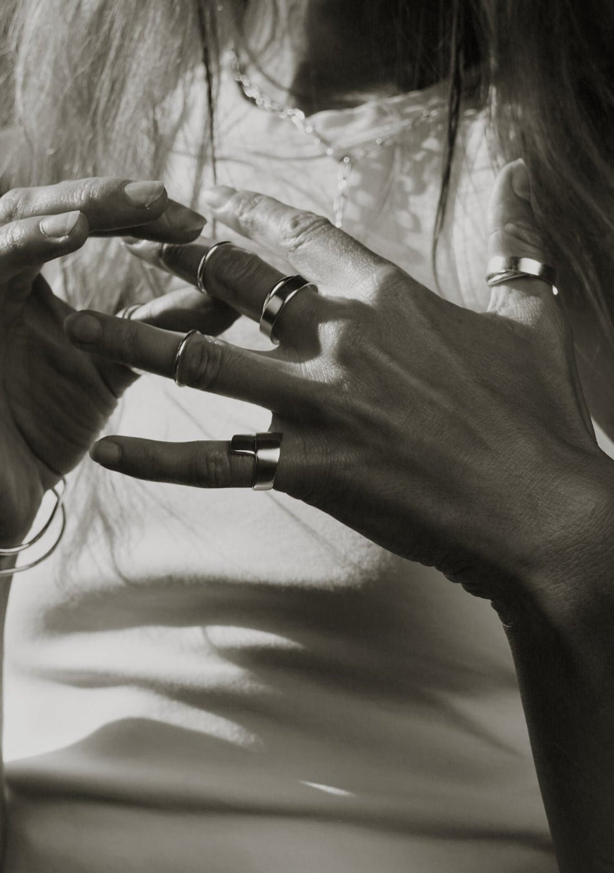 1. Woman's hands adorned with multiple silver rings including Milky Way ring by NO MORE, in a monochrome setting