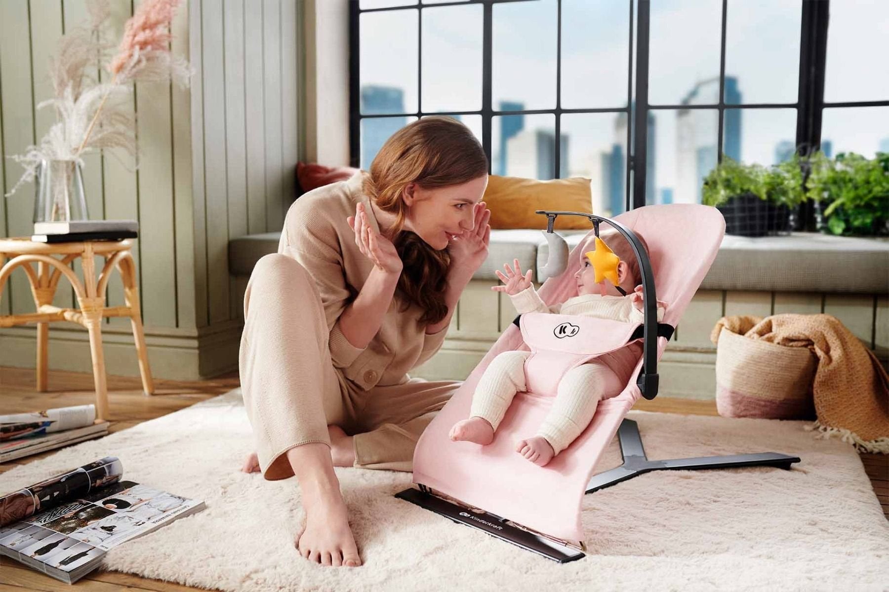 1. Woman interacting with baby in pink Kinderkraft MIMI bouncer in cozy living room setting