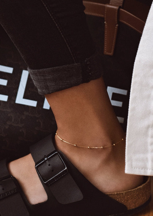 1. Women's Mini Bubble Anklet in gold worn on ankle, styled with casual footwear, showcasing minimalist elegance