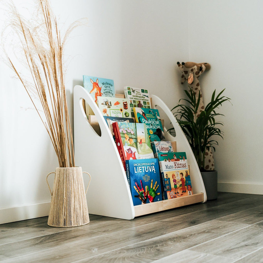 7. Montessori bookshelf with books in a corner of a room with plant and giraffe decor