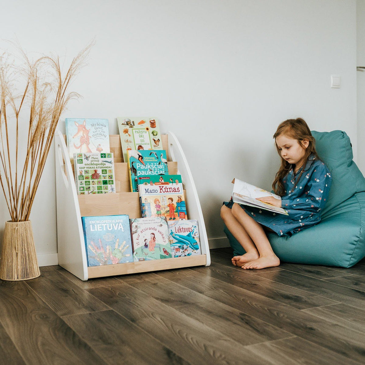 5. Girl reading next to Montessori bookshelf filled with books in a cozy room setting