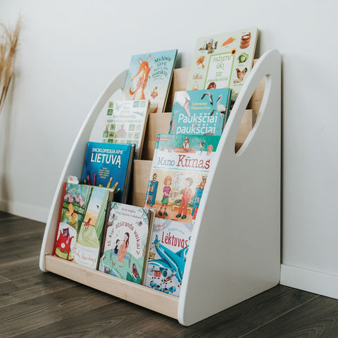 1. Montessori bookshelf with four shelves displaying children's books in a bright room with wooden flooring