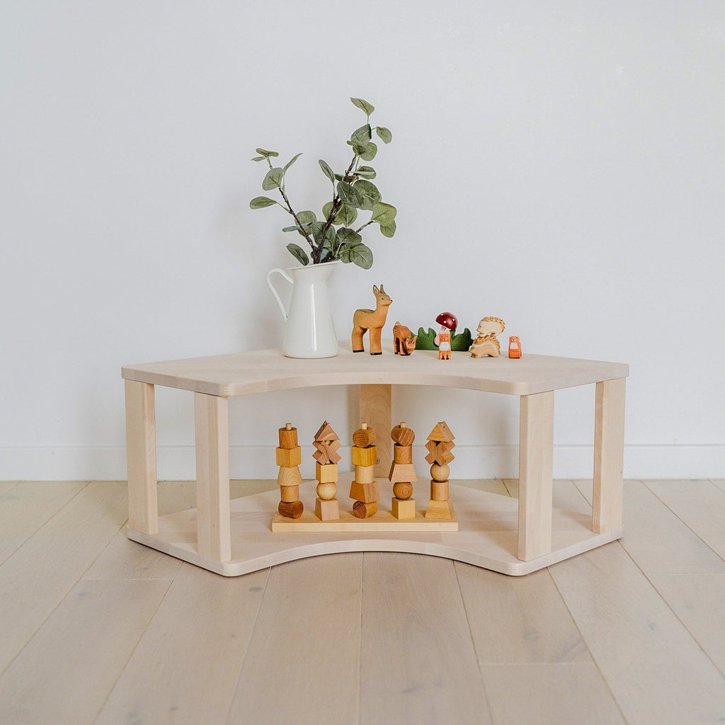 1. Solid wood Montessori corner shelf with toys and plant on top in a bright room