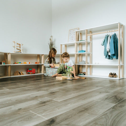 2. Two children playing near modular Montessori shelves with toys and clothes in a bright room