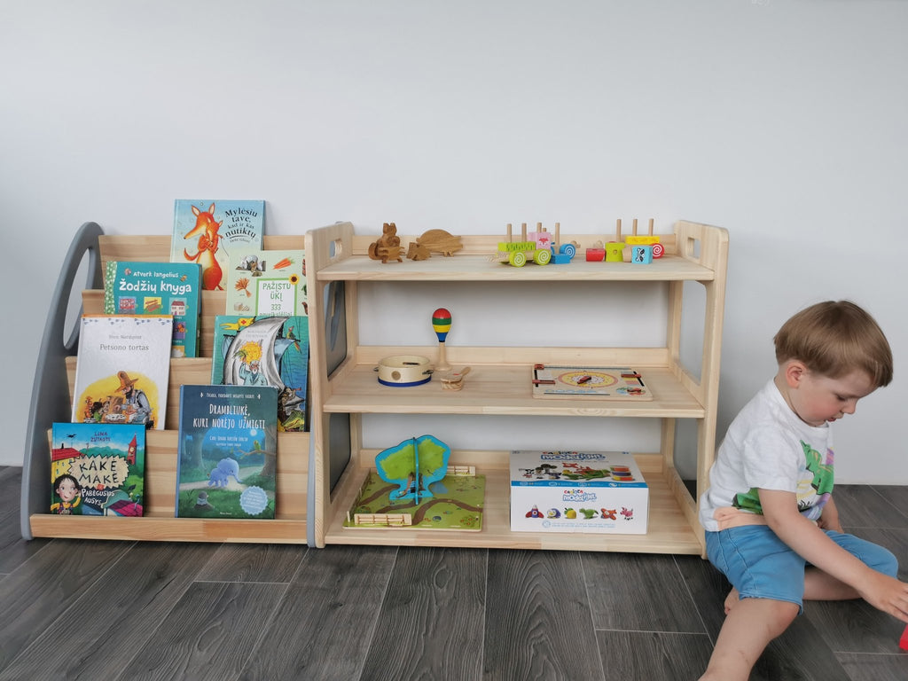 5. Child playing next to two Montessori toy shelves filled with books and toys, in a natural wood finish