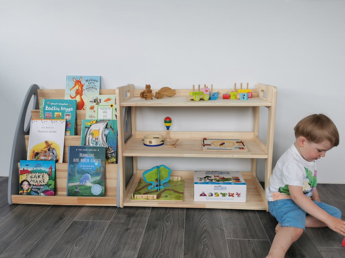 5. Child playing next to two Montessori toy shelves filled with books and toys, in a natural wood finish