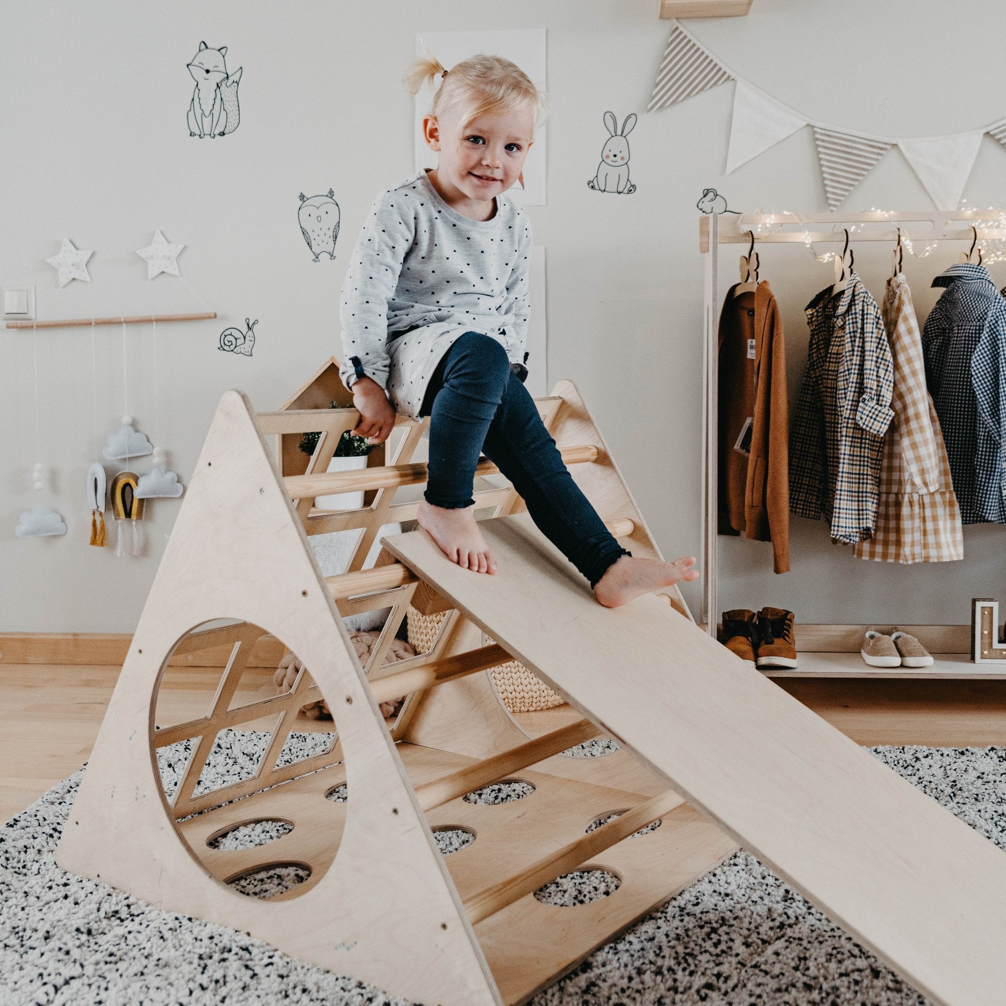 1. Toddler girl in polka dot dress climbing Montessori wooden triangle with ramp in playroom