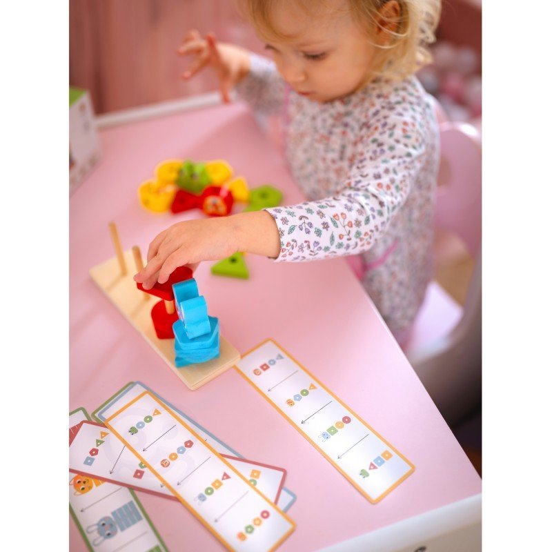 4. Child playing with Montessori puzzle pyramid and pattern cards on pink table