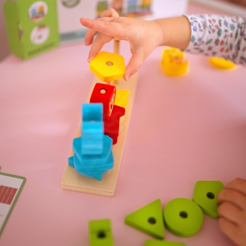 3. Child stacking yellow block on Montessori puzzle pyramid with colorful animal shapes on pink table