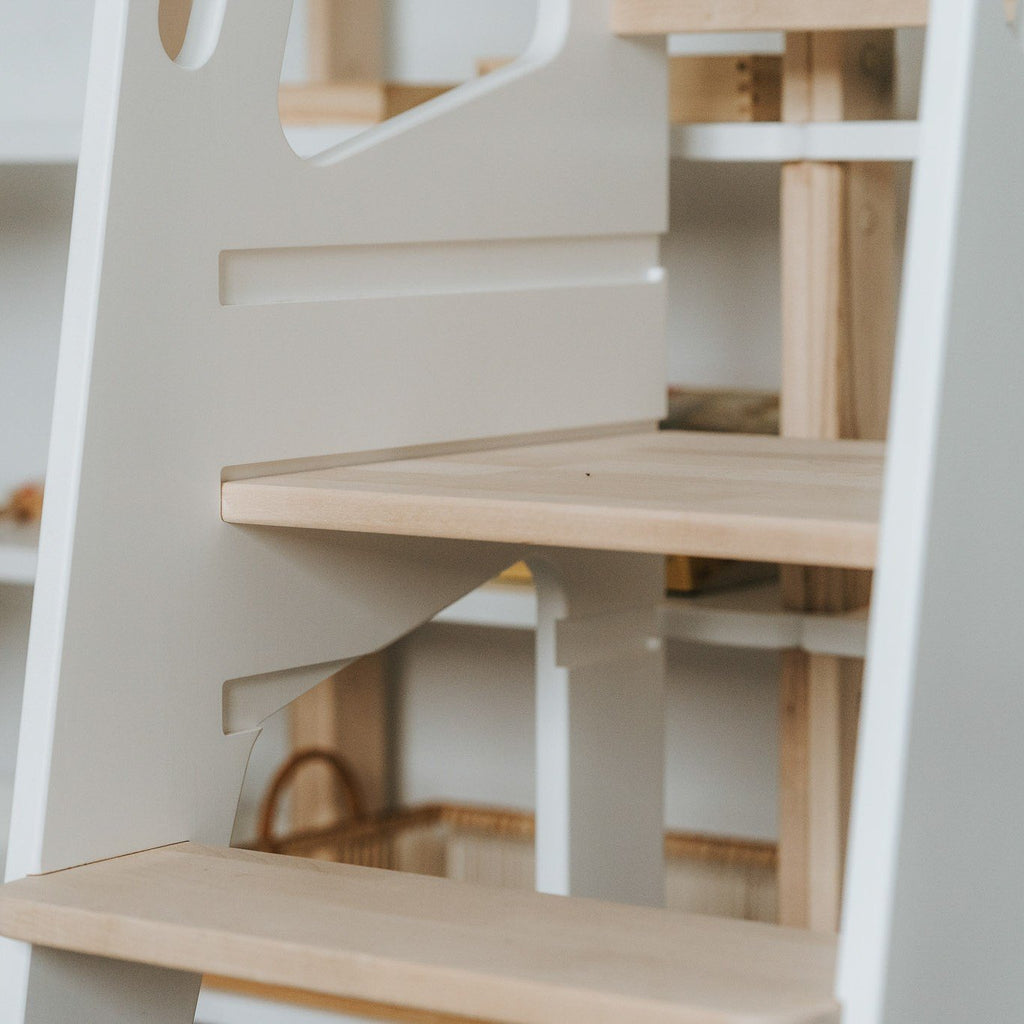 3. Close-up of Montessori Tower Safety+ steps and side panel in white finish, showing craftsmanship and material quality