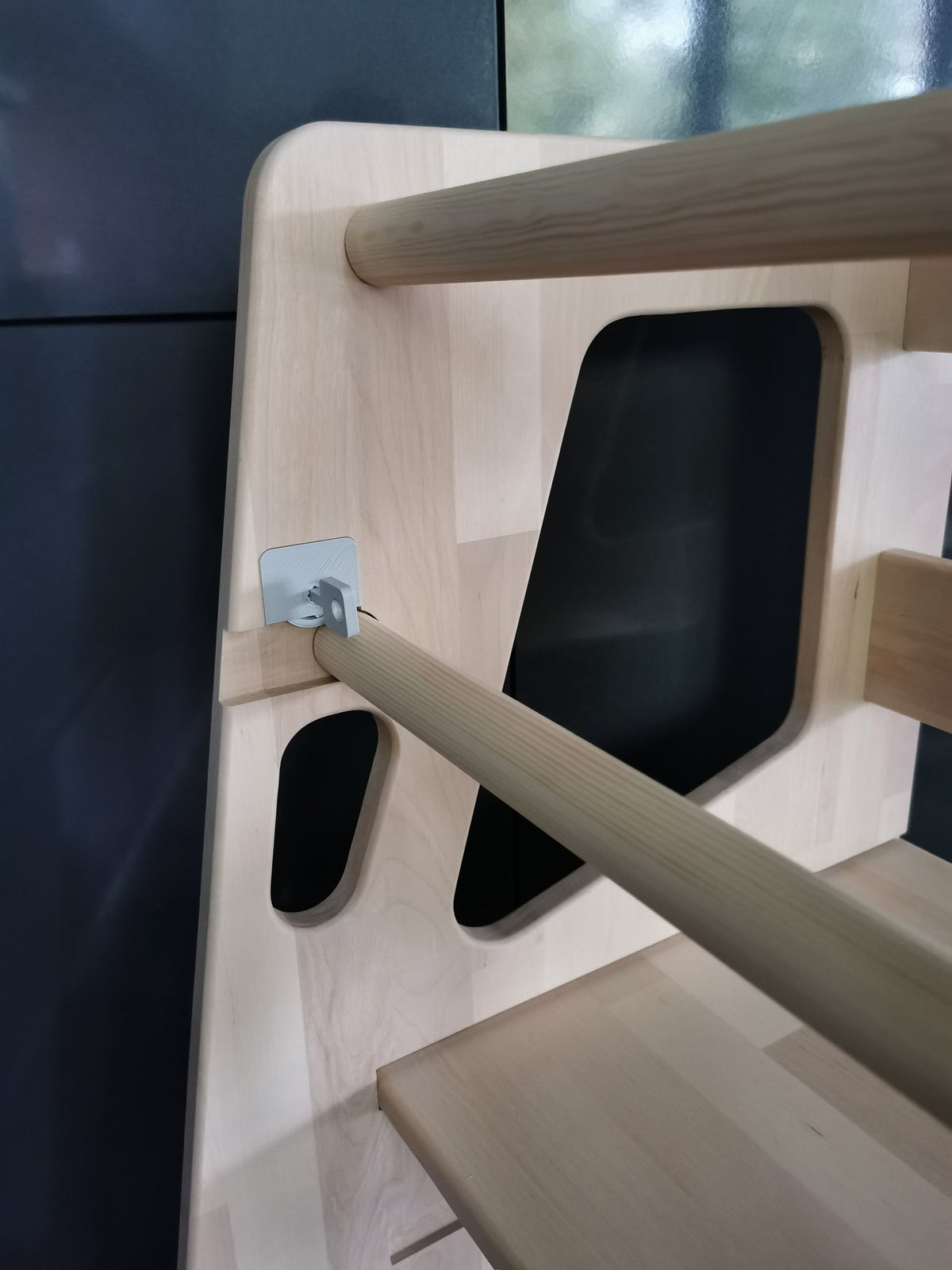 3. Close-up of Montessori Tower Safety+ side panel and safety bar in natural wood finish, showcasing design details