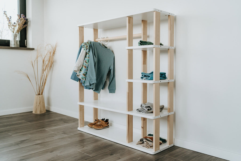 2. Side view of Montessori wardrobe with white shelves and natural wood accents, displaying children's clothing and shoes, set against a white wall
