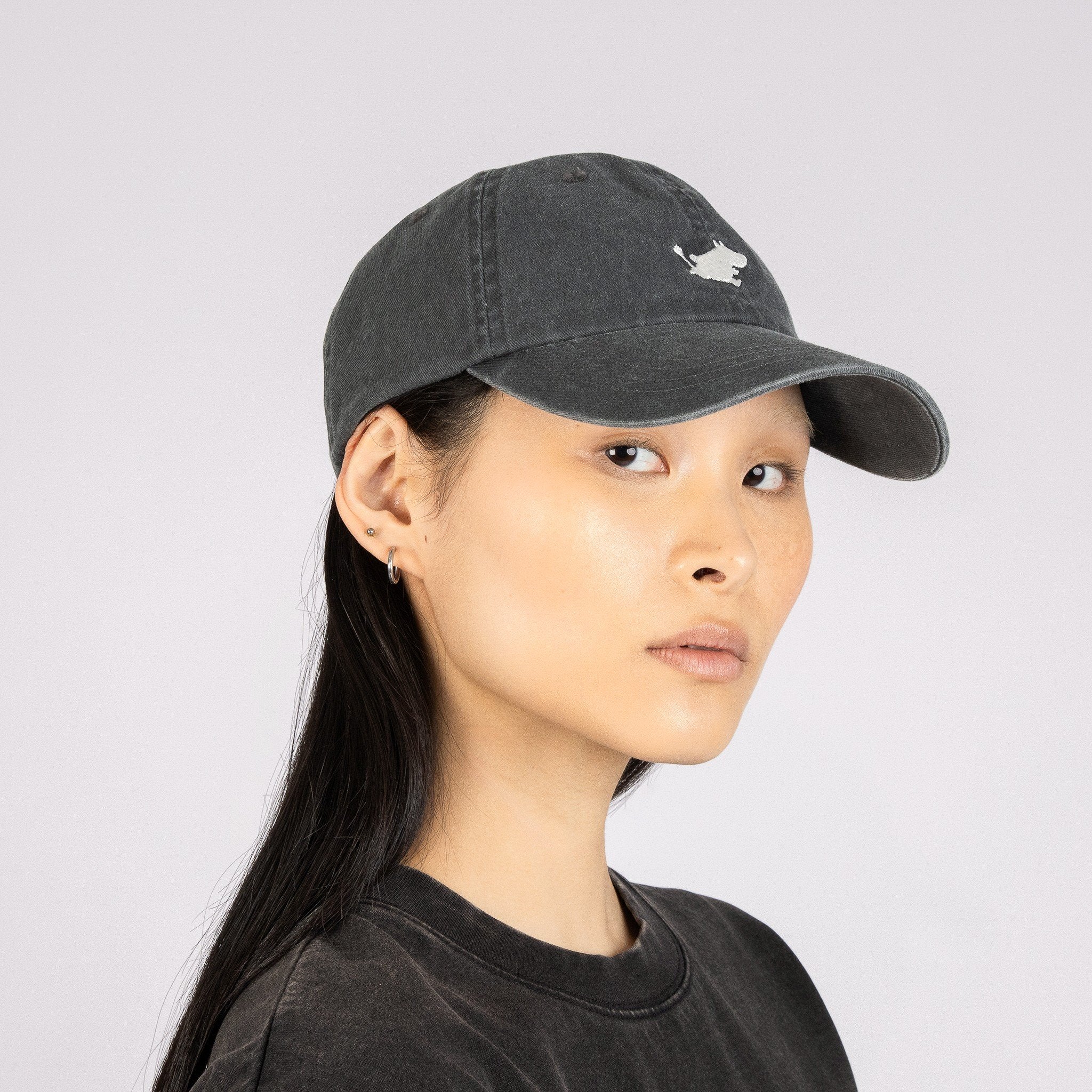 1. Woman wearing Moomin Classics Denim Dad Cap in dark grey, showcasing adjustable fit and embroidered logo