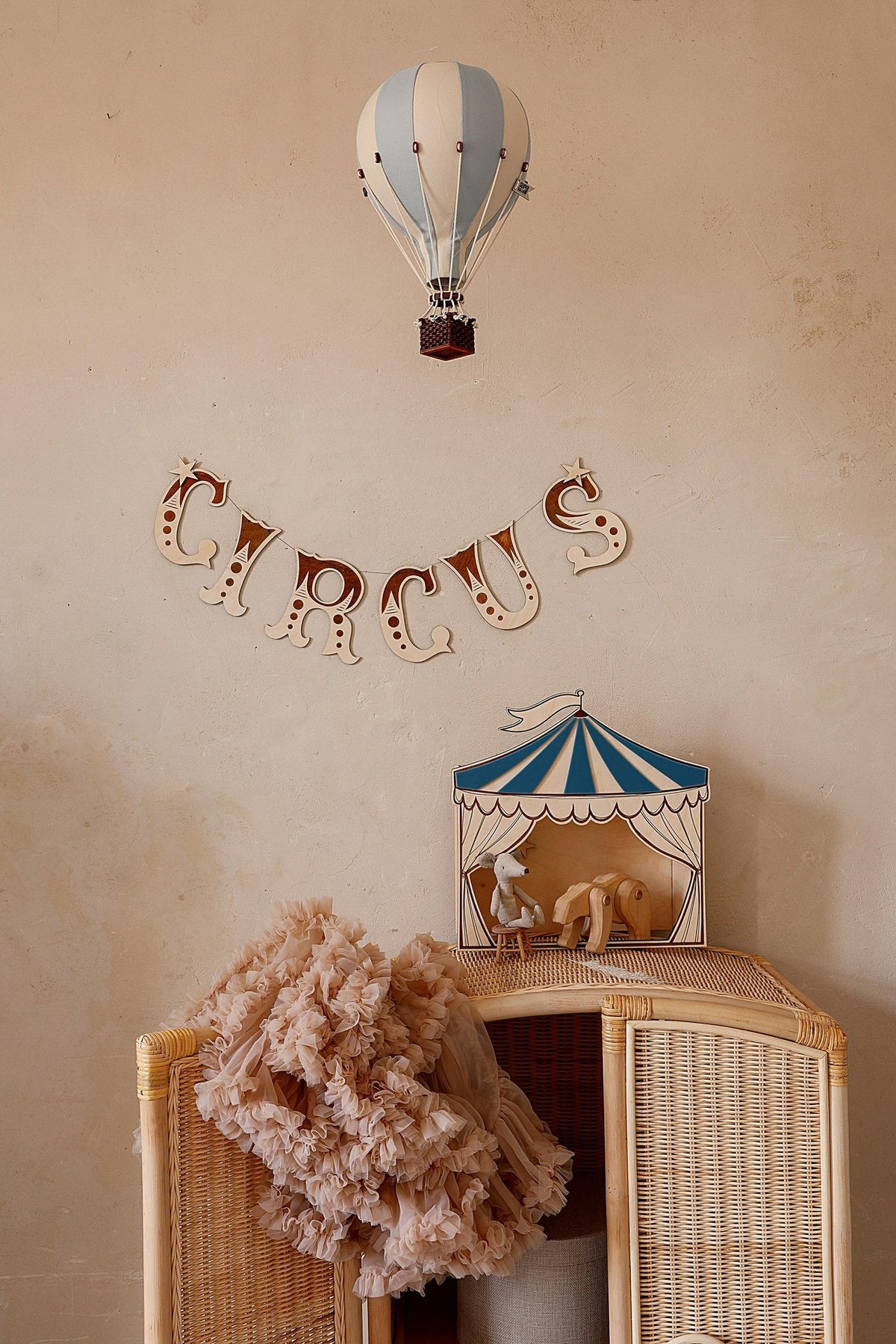 1. Wooden wall garland spelling 'CIRCUS' in a child's room with a wicker cabinet and hot air balloon decor