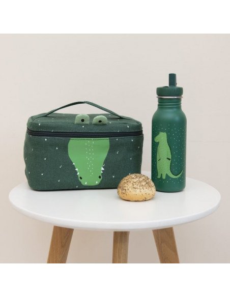 4. Green Mr. Crocodile thermal lunch bag and matching bottle on a white table with a bun, showcasing playful design