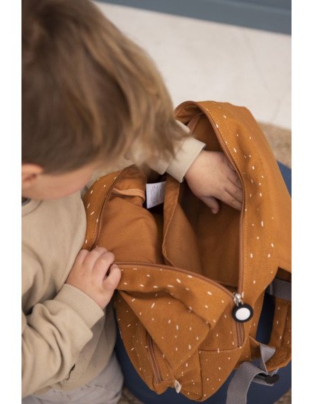 1. Child opening Trixie Baby Mr. Tiger backpack, showing interior space in a home environment