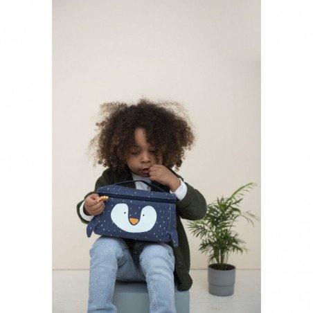 1. Child holding Trixie Baby Mr. Penguin lunch bag, sitting on stool, highlighting playful design