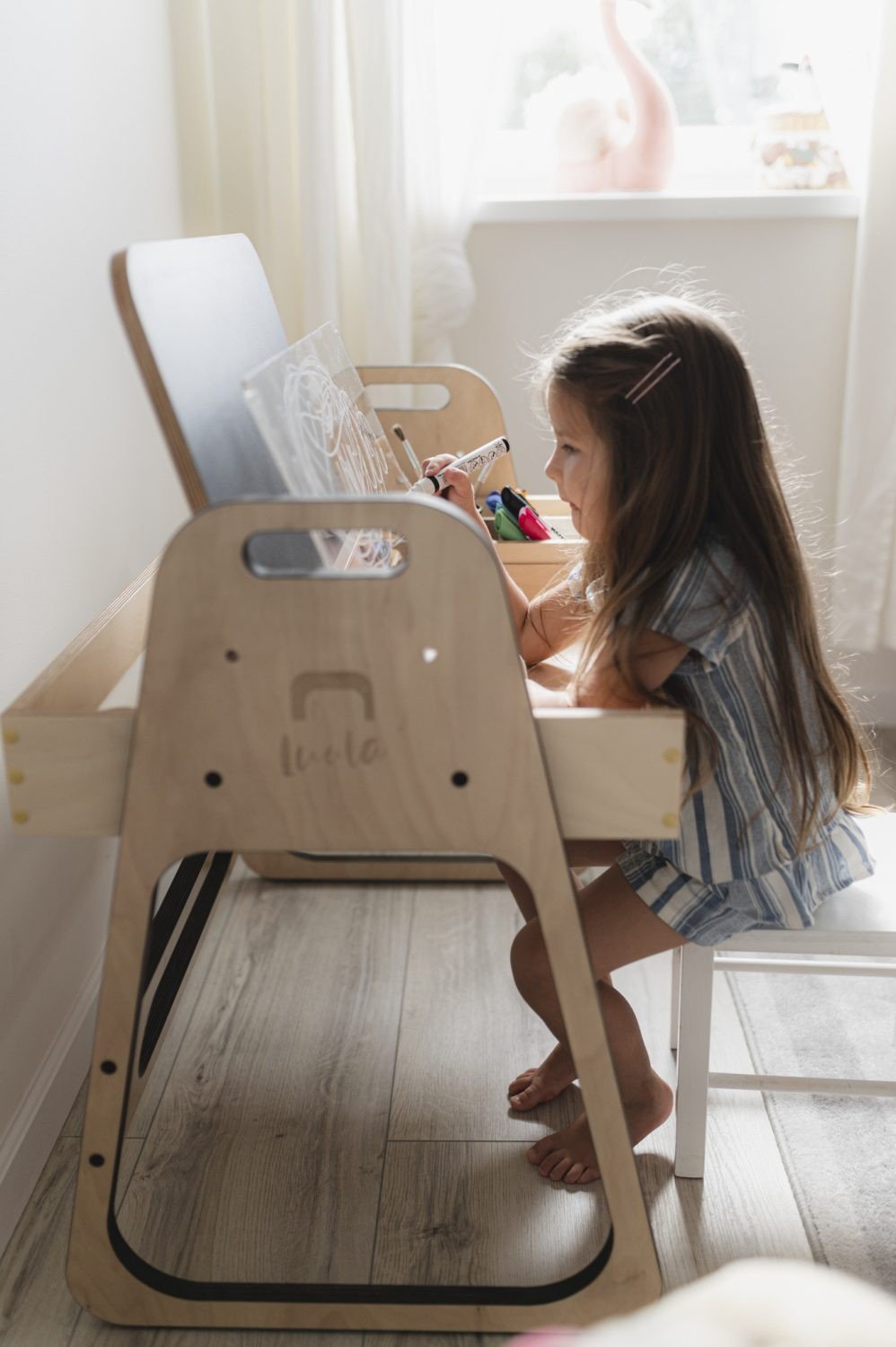 1. Girl sitting at Luula Julle table drawing with chalk in a sunlit room