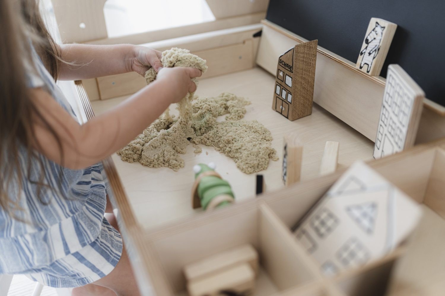 6. Close-up of child playing with sand on Luula table, highlighting tactile play and storage compartments