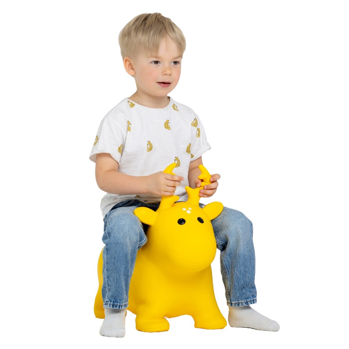 1. Young boy sitting on yellow moose-shaped hopper toy, wearing white t-shirt with yellow print and blue jeans, in a studio setting