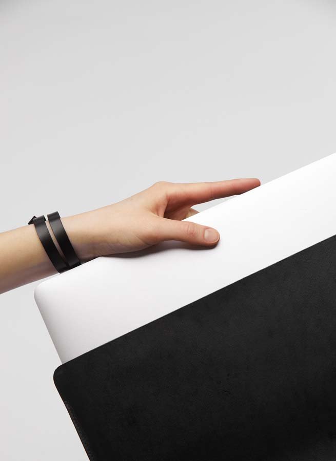 6. Hand inserting laptop into black leather sleeve