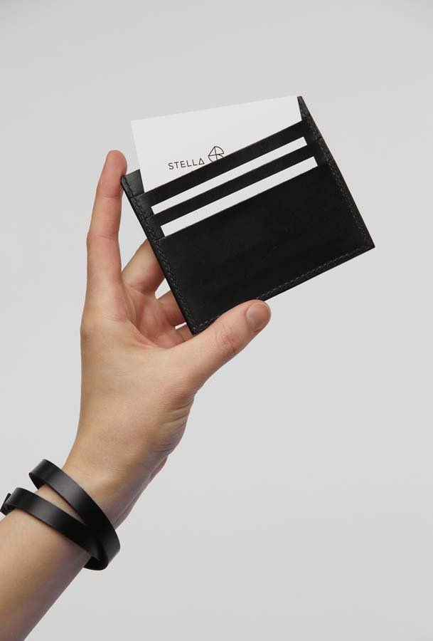 1. Hand holding black Stella Soomlais slim fit leather wallet with cards inserted, showcasing minimalist design