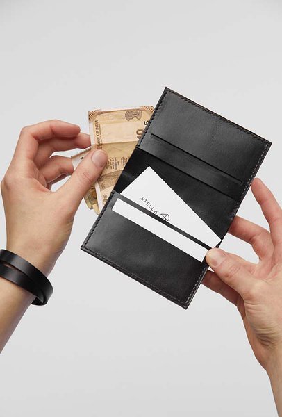 1. Person holding open black leather wallet with cash and cards visible, showcasing interior pockets