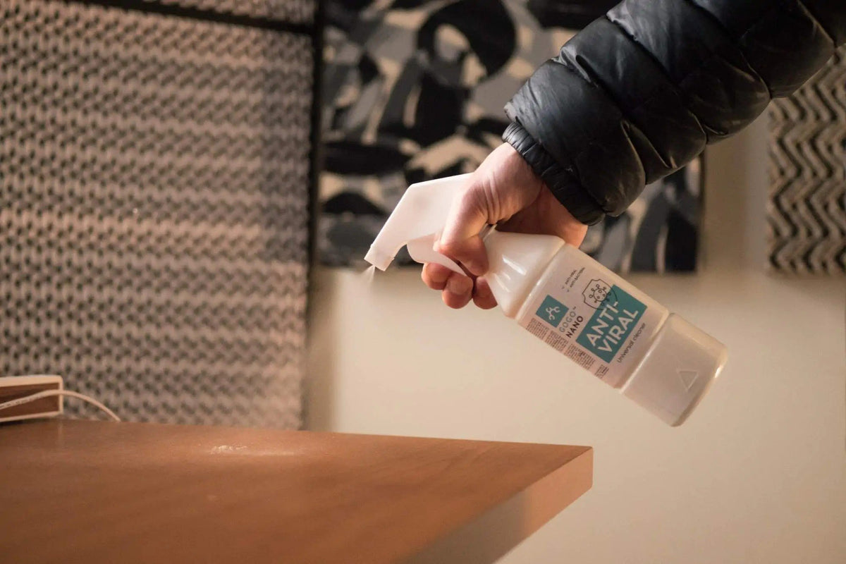 1. Hand spraying GoGoNano Anti-Viral cleaner on wooden table in home setting