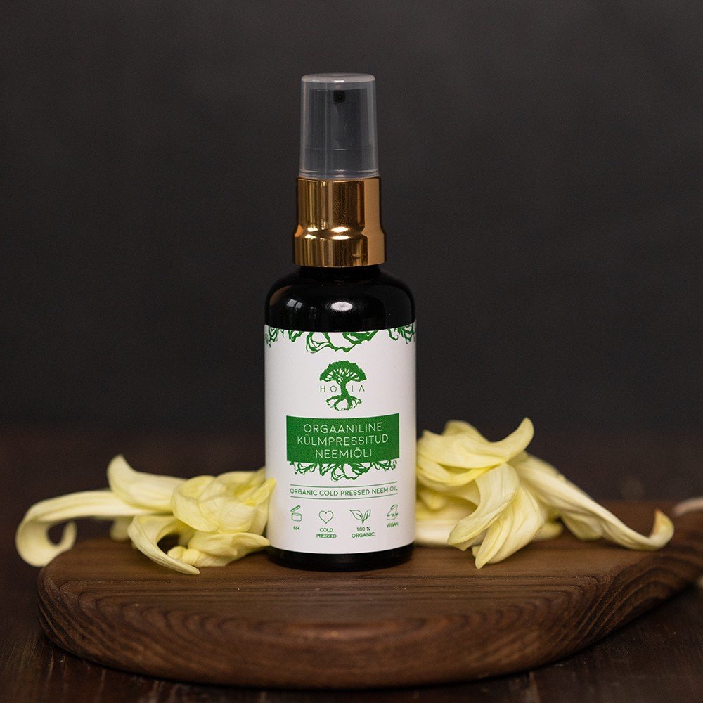 2. HOIA homespa neem oil bottle on wooden board with yellow flowers, highlighting organic cold-pressed formula