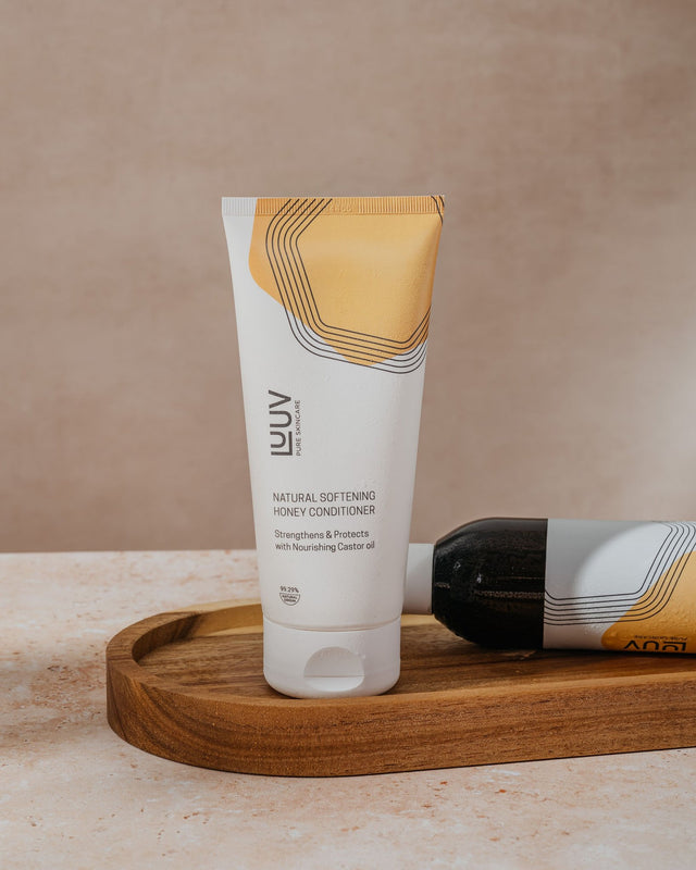 3. LUUV Natural Softening Honey Conditioner tube on wooden tray, emphasizing nourishing castor oil and eco-friendly packaging
