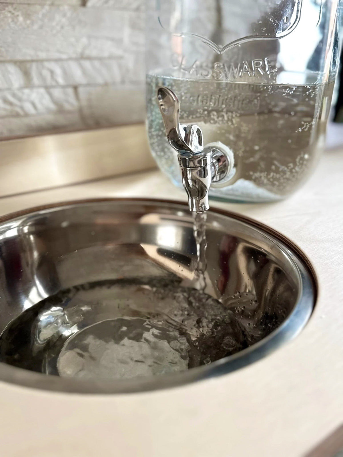 7. Close-up of water pouring into enamel bowl on Montessori washbasin