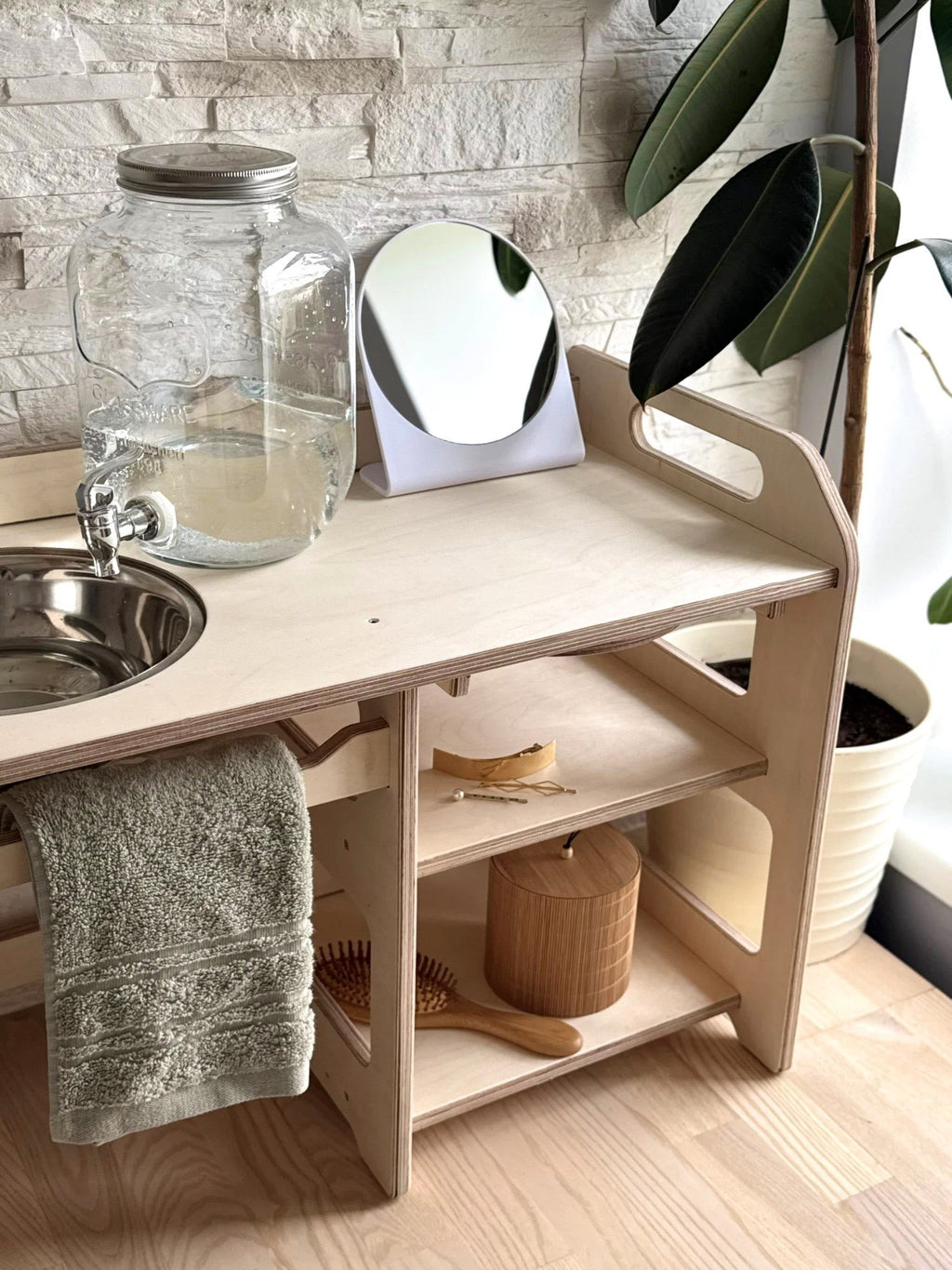 8. Montessori washbasin with towel, mirror, and storage shelves in a bright room