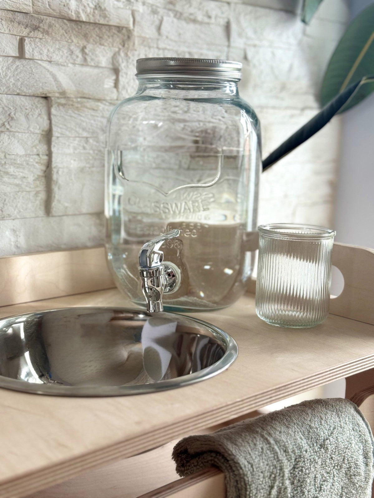 8. Glass jar and steel bowl on Montessori washbasin, highlighting water flow and textured glass