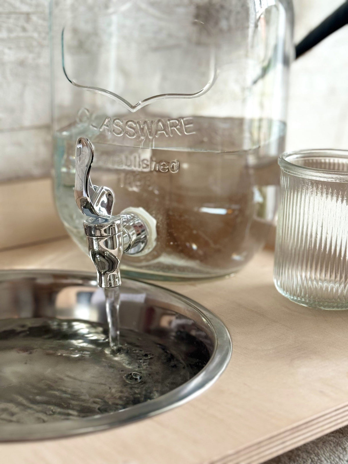 9. Close-up of water flowing from glass jar into steel bowl on Montessori washbasin