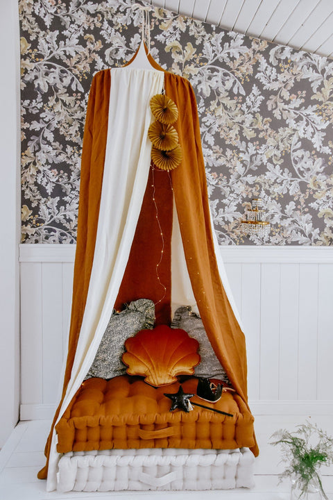 2. Caramel and cream canopy over a cozy bed with decorative pillows and floral wallpaper