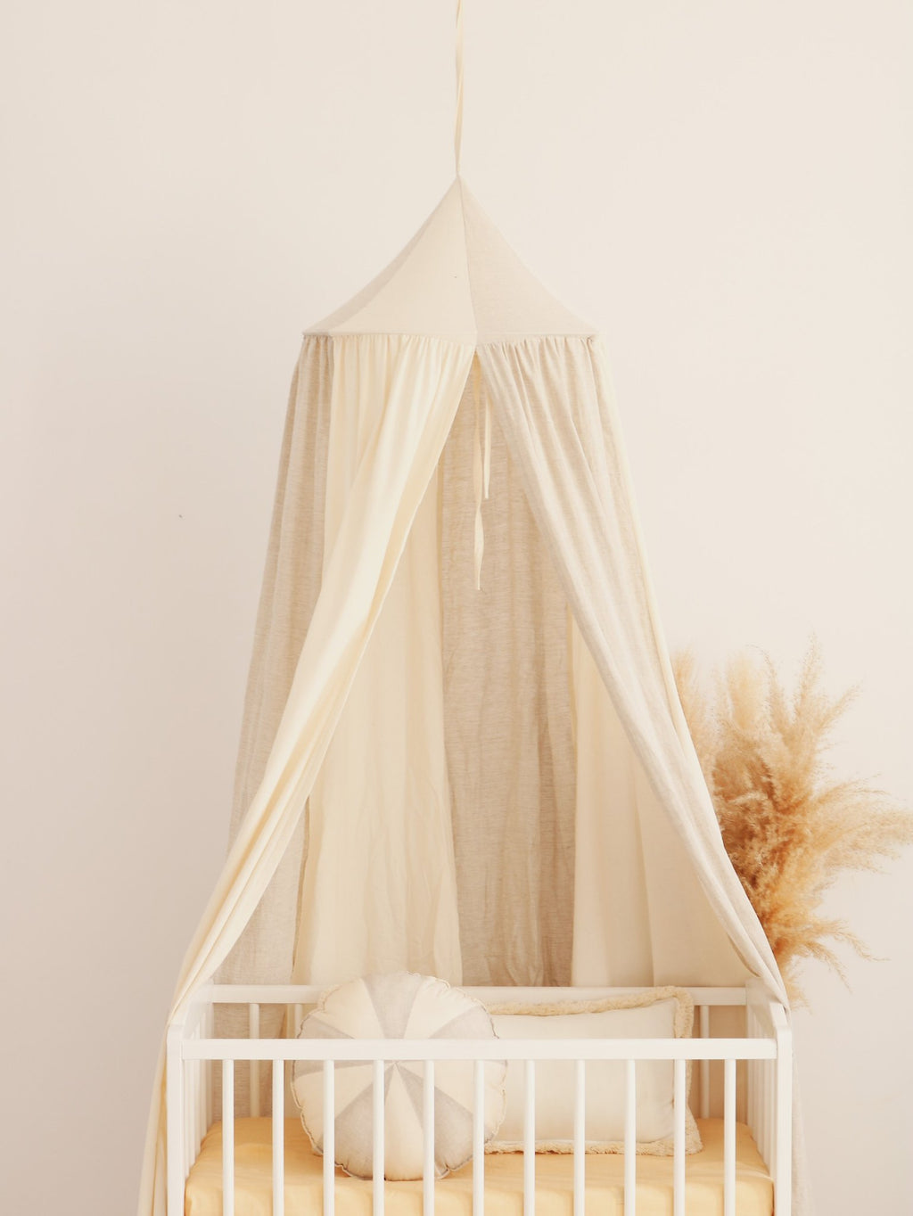 9. Cream canopy over crib with pampas grass in a nursery