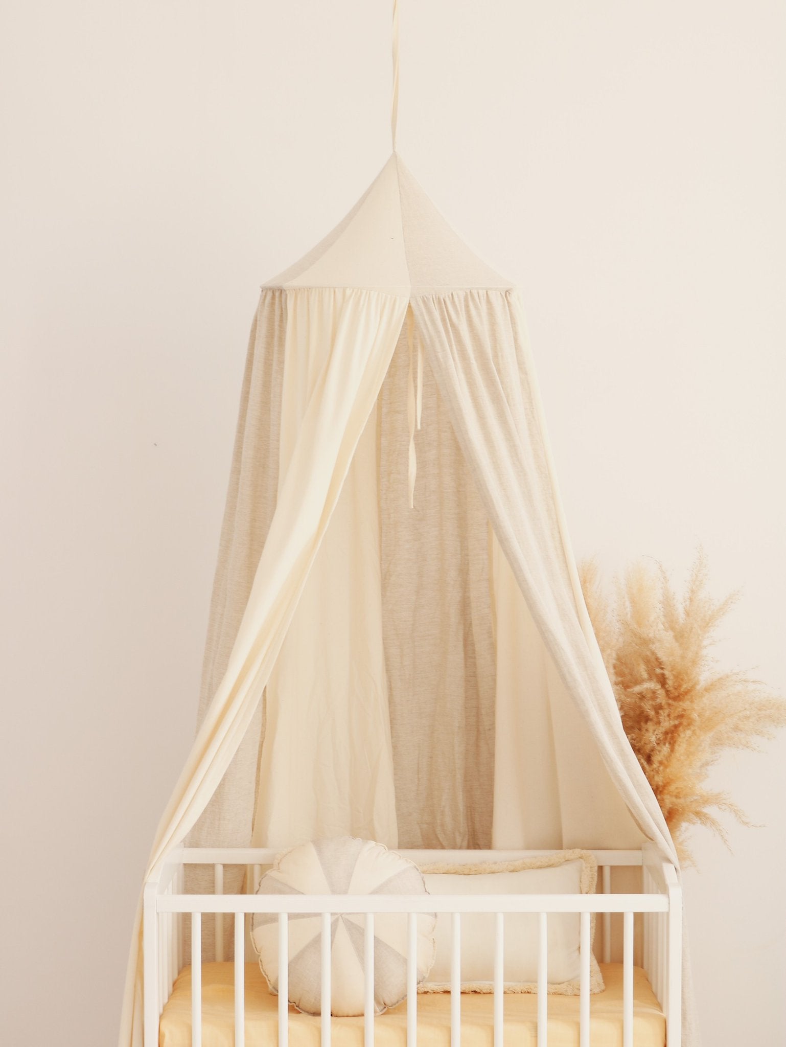 9. Cream canopy over crib with pampas grass in a nursery