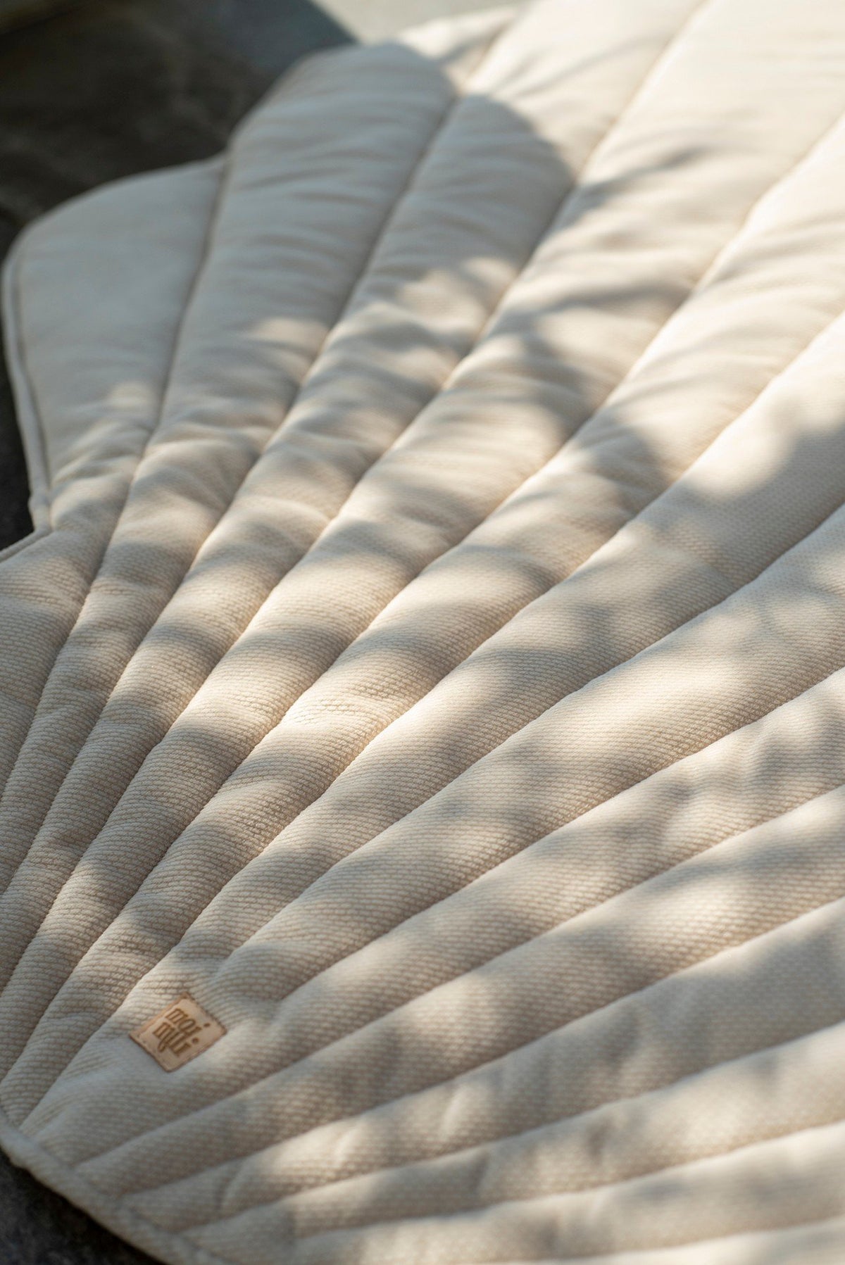 12. Close-up of beige ginkgo leaf-shaped playmat with shadow patterns and logo