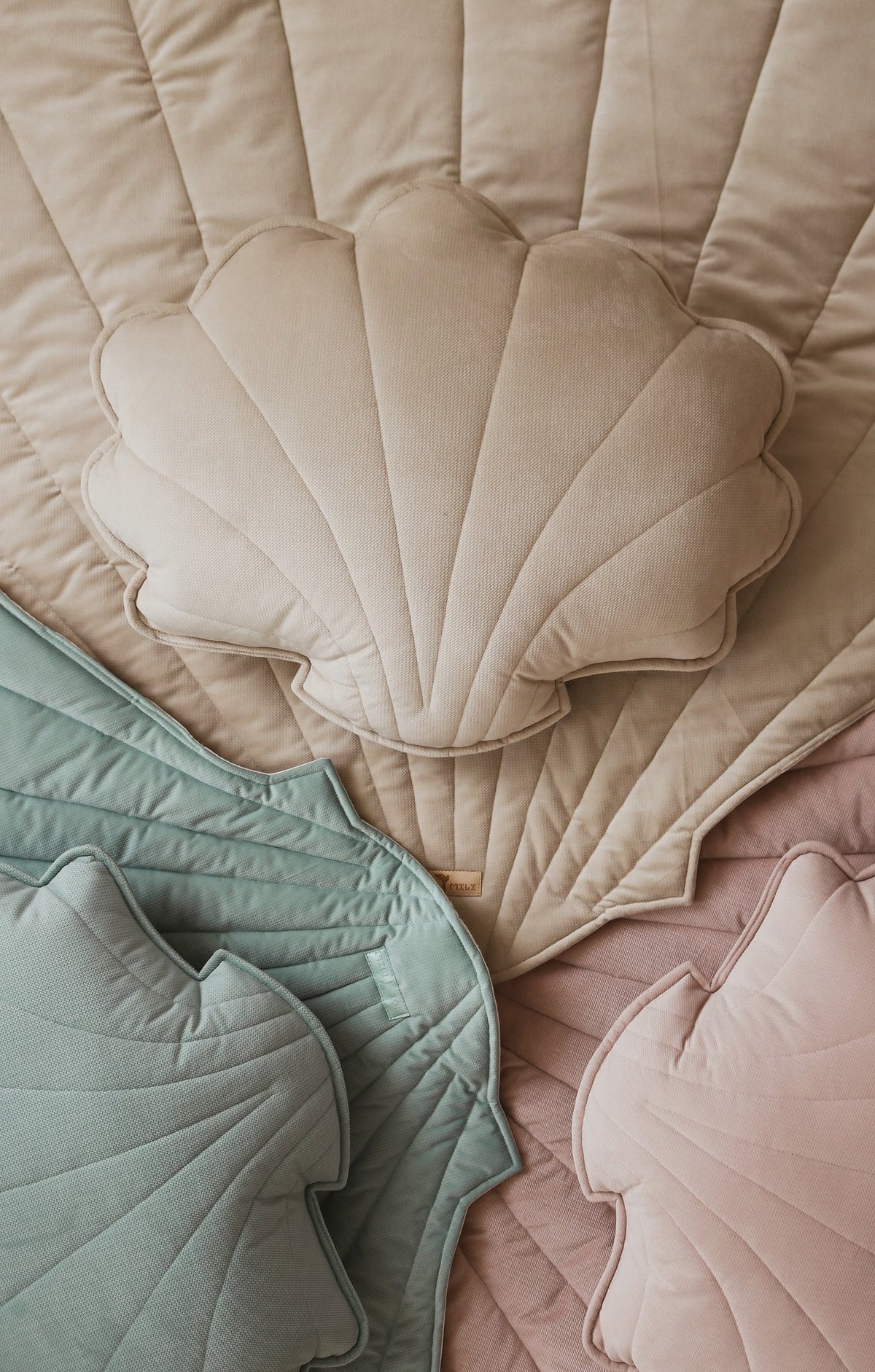 7. Close-up of beige, pink, and green ginkgo leaf-shaped playmats with shell cushions