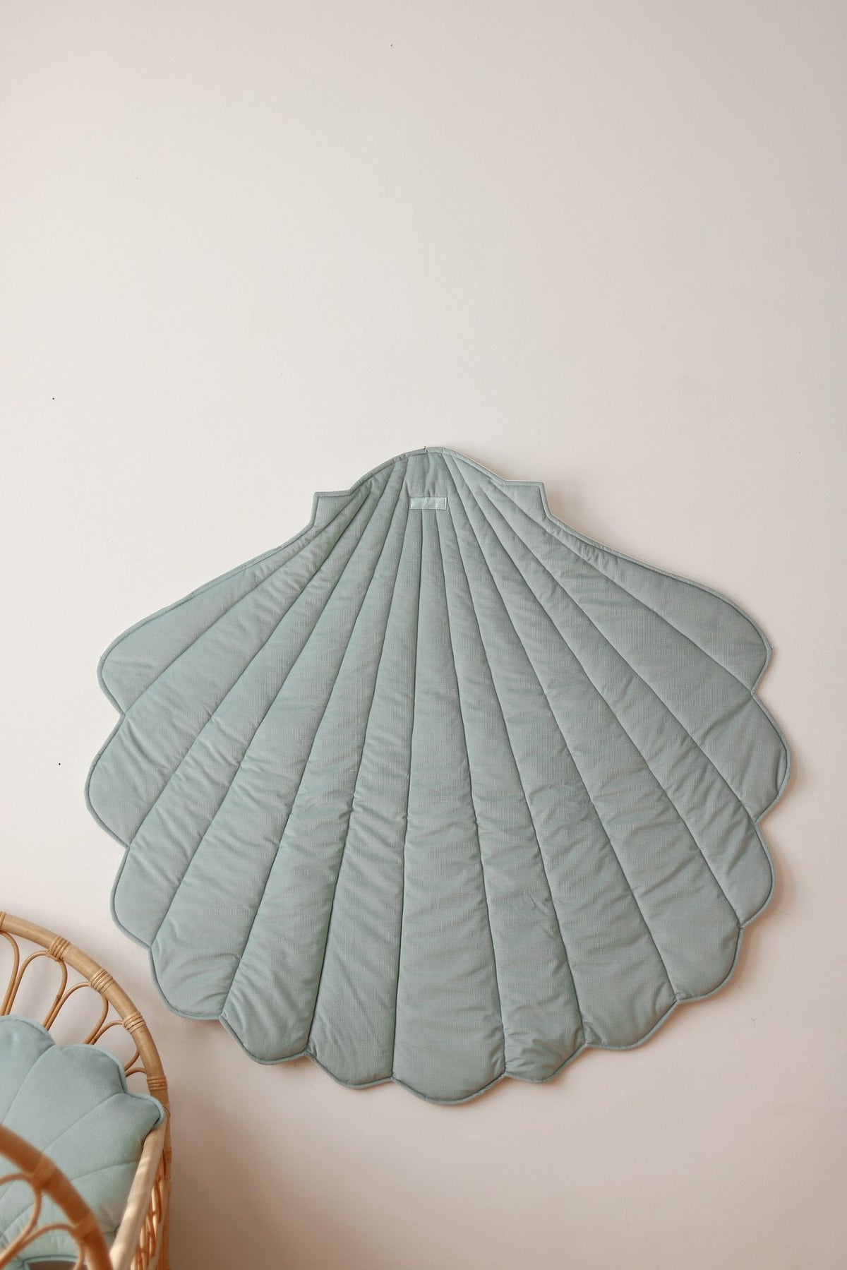 2. Mint green shell-shaped playmat displayed on wall next to wicker crib