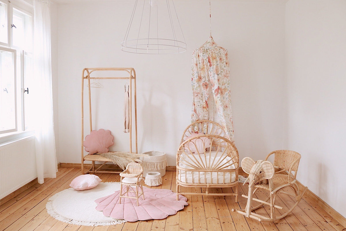 10. Powder pink shell playmat in a nursery with rattan furniture and floral canopy