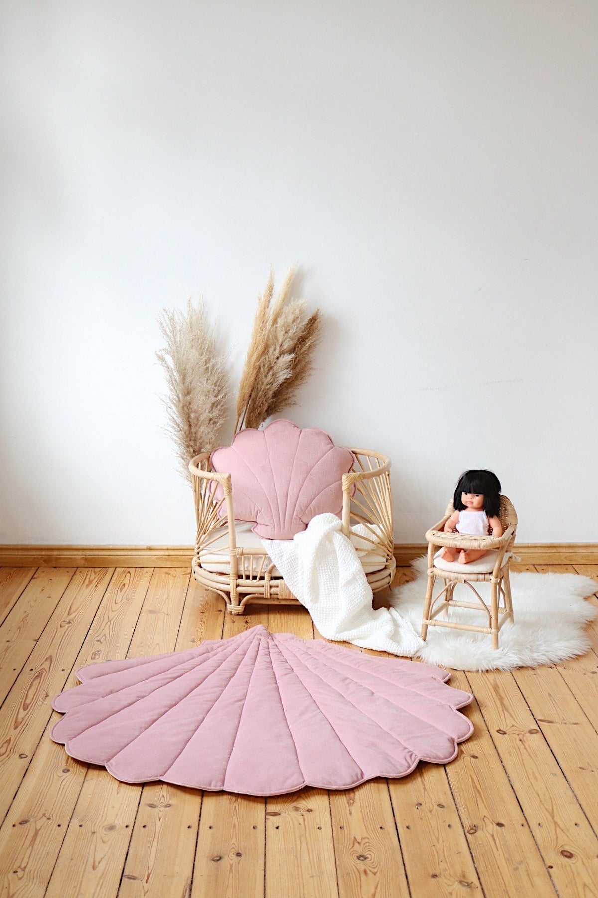 6. Powder pink shell playmat with doll and rattan chair in minimalist nursery