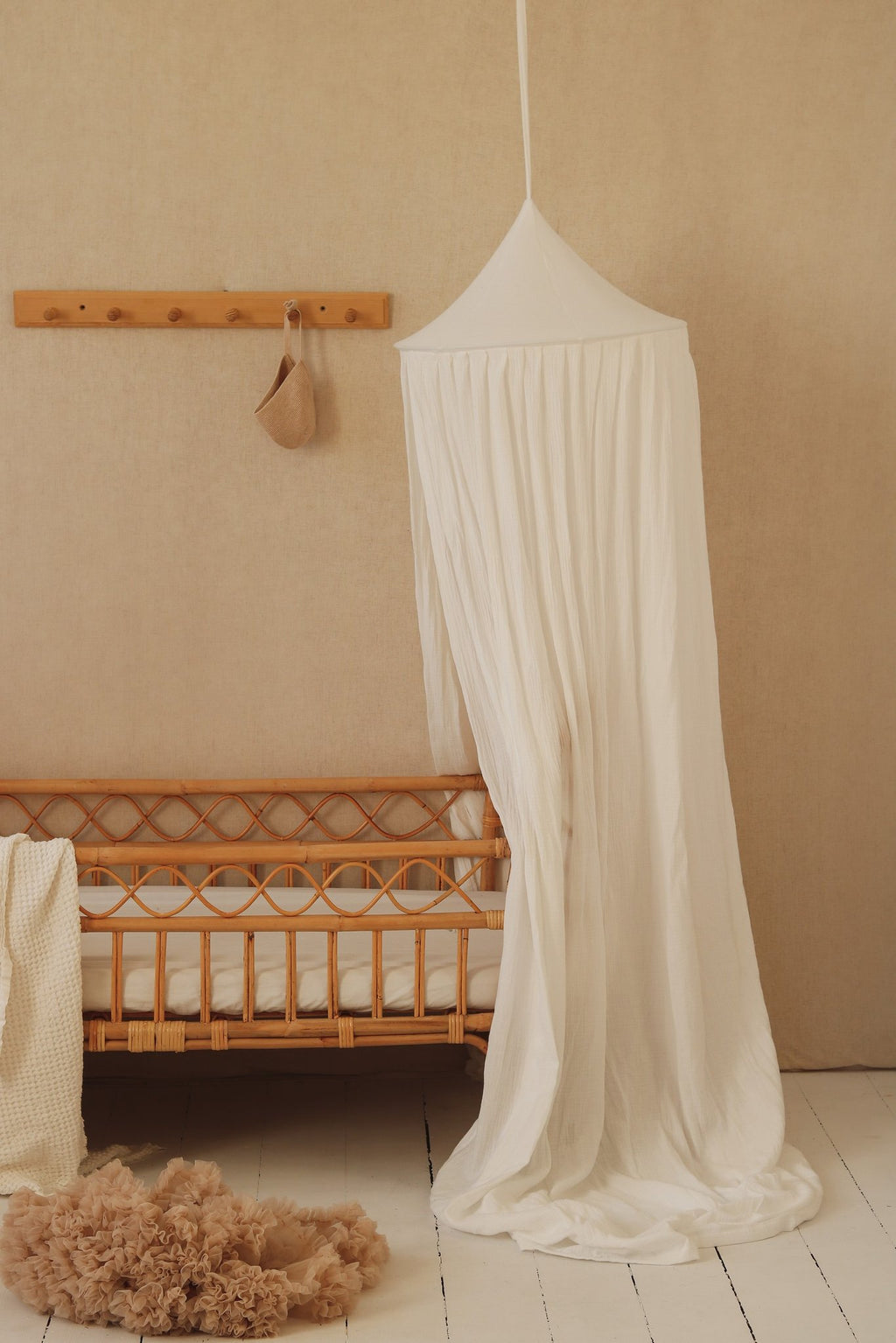 1. Cream cotton canopy over a crib in a nursery with a soft rug and wall decor
