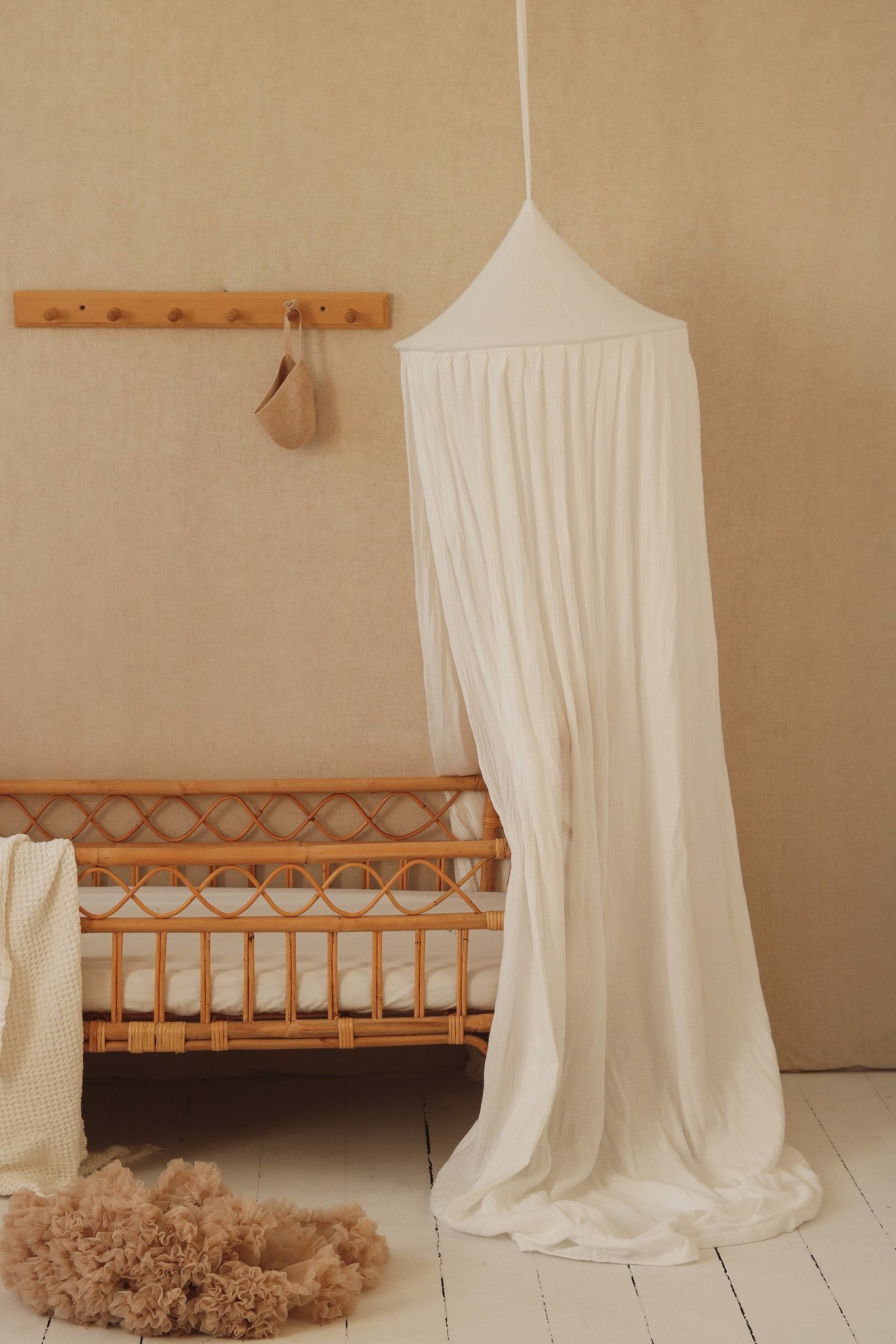 1. Cream cotton canopy over a crib in a nursery with a soft rug and wall decor