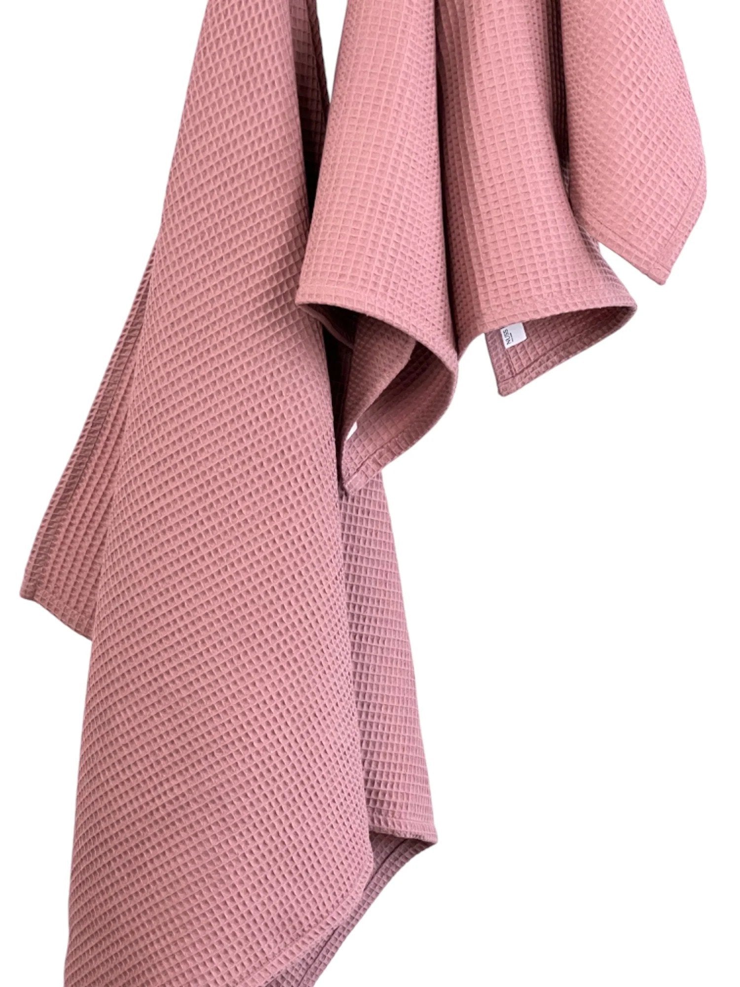 6. Detail of old pink waffle cotton towels hanging, emphasizing fabric texture