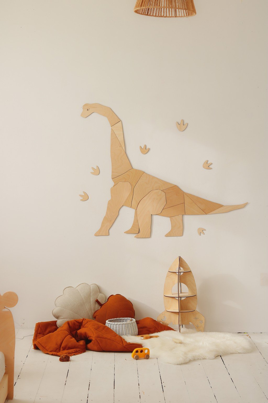 4. Wooden diplodocus wall decoration in child's room with orange and white decor and dinosaur footprints