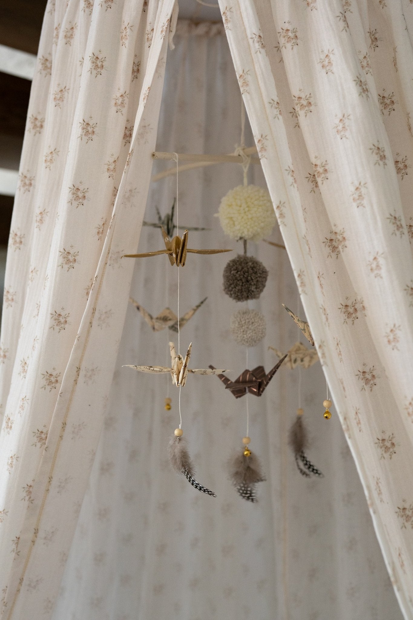 6. Moi Mili origami mobile with paper cranes and pompoms hanging inside floral-patterned canopy
