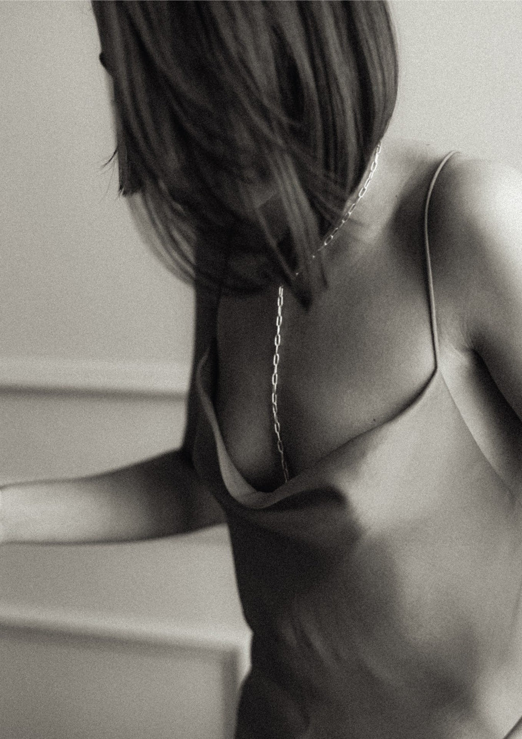 8. Black and white image of woman wearing silver Y-shaped necklace with open back dress