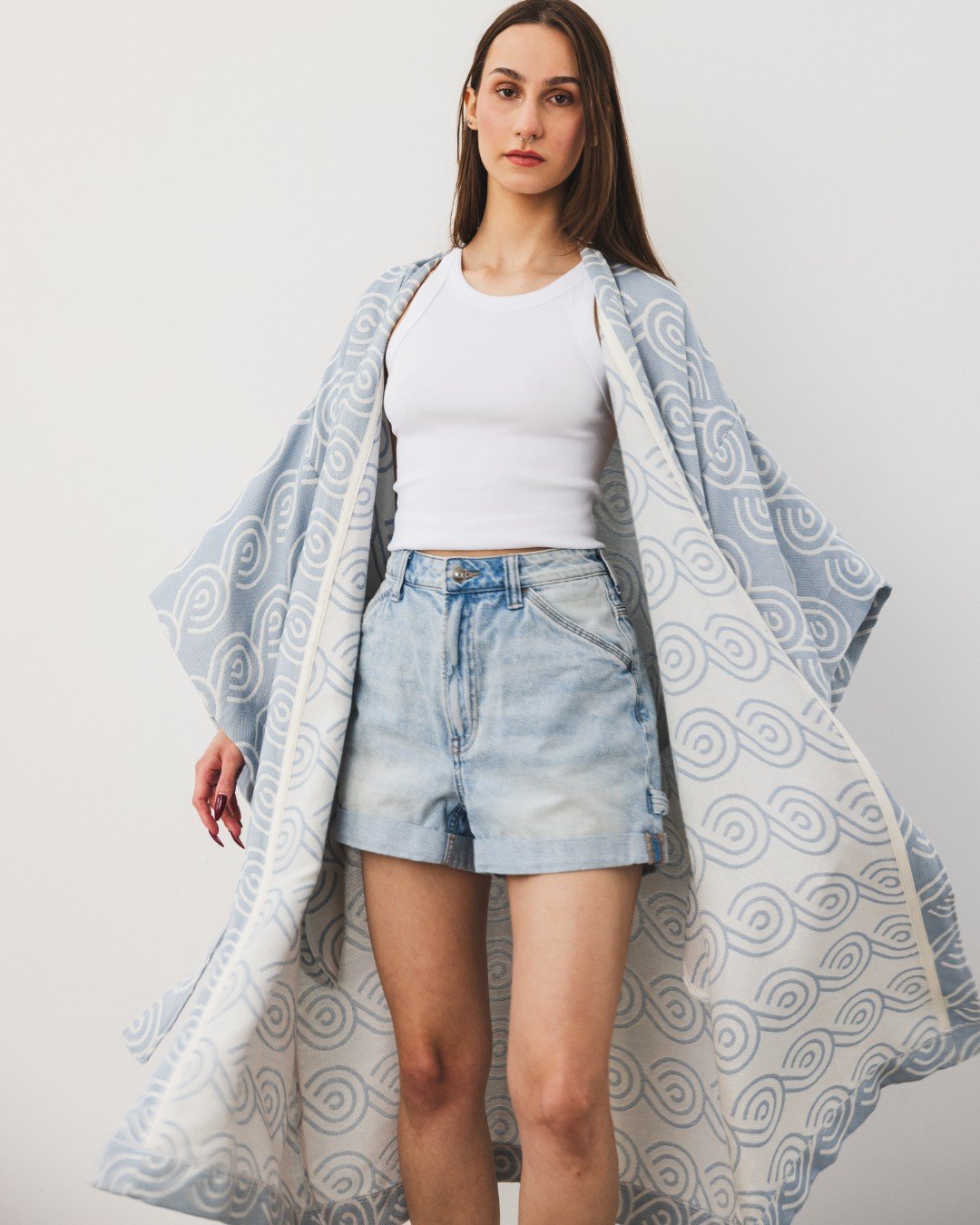 7. Woman wearing Patulove blue bamboo kimono over white top and denim shorts, arms outstretched