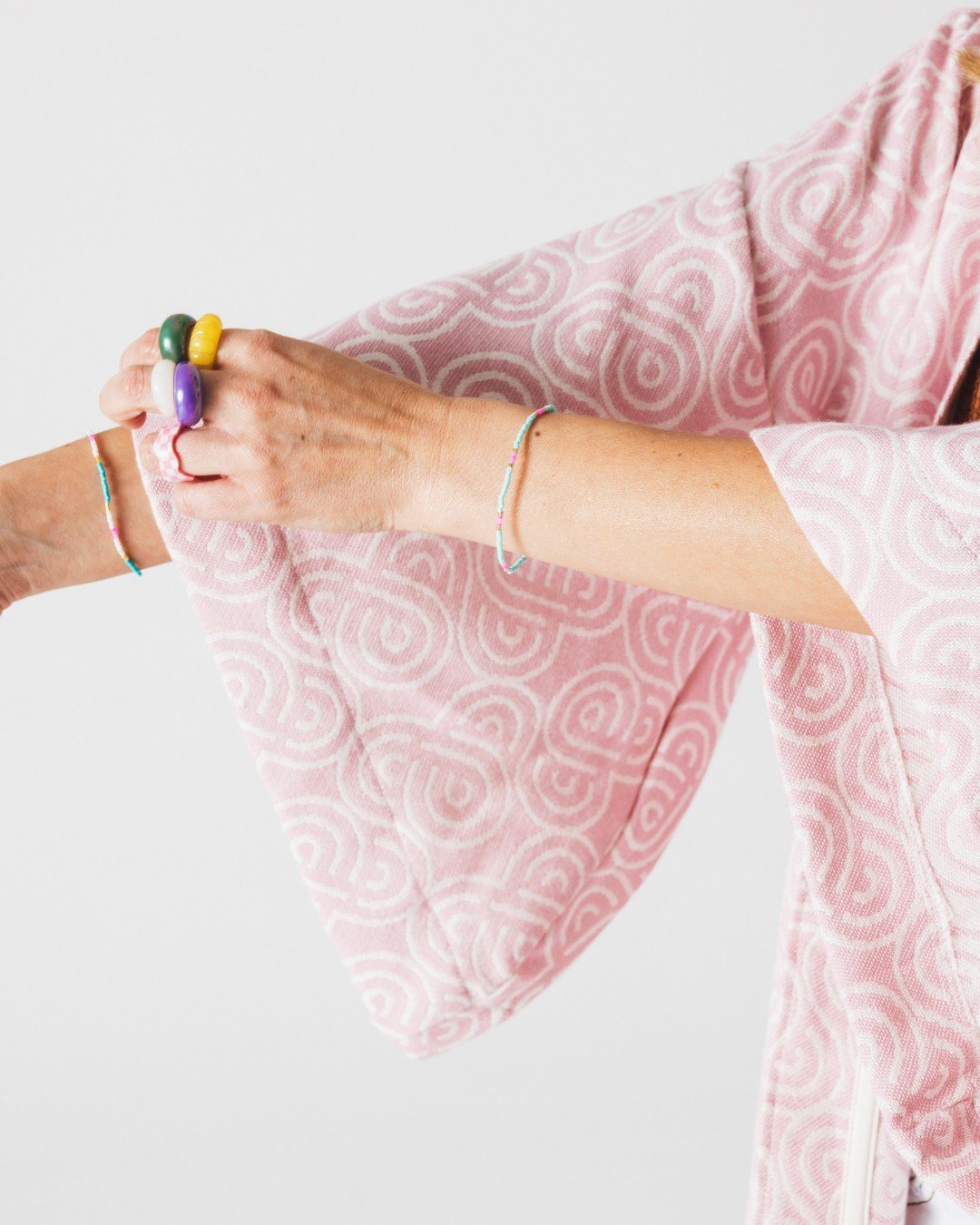 4. Close-up of Patulove rose bamboo kimono sleeve with spiral pattern, showing colorful rings and bracelets